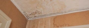 What Causes Damp? Signs of dampness in the corner of a ceiling.